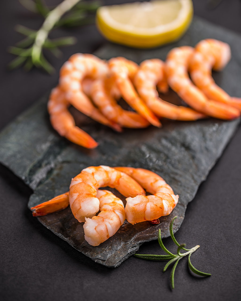 Pile of fresh raw shrimp on dark wet slate with ice