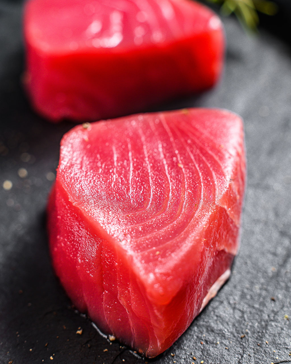Whole tuna and sliced loins on dark slate